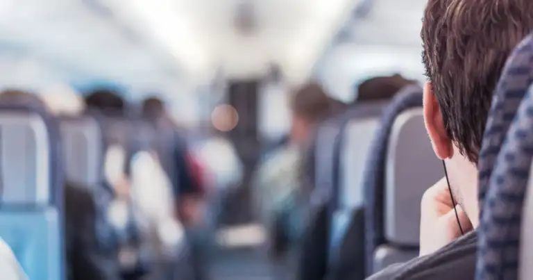 Interior de avión con pasajeros sentados en sus asientos