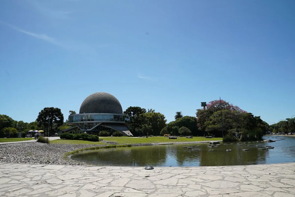Planetario de domo geodésico junto a laguna en parque