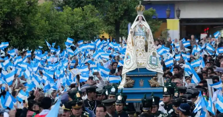 Multitud en celebración religiosa con banderas azules y estructura central