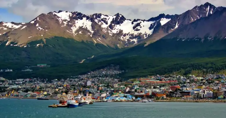 Ciudad costera con montañas nevadas al fondo
