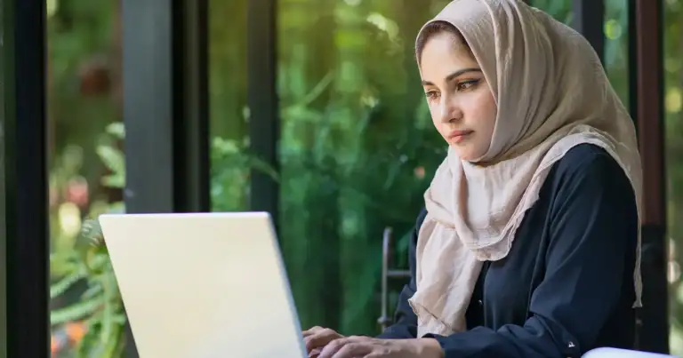 mujer musulmana con pañuelo en la cabeza usando una laptop