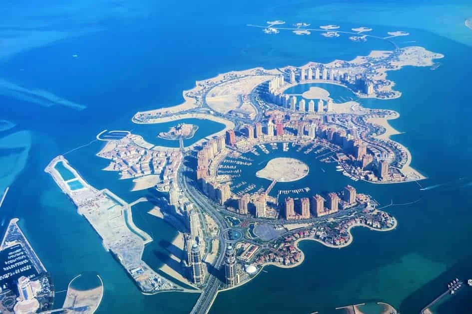 Vista aérea de edificios modernos, palmeras artificiales y aguas turquesas