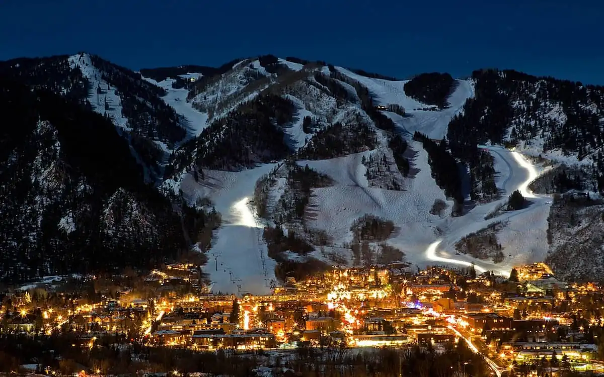Pueblo de Aspen iluminado al anochecer bajo montañas nevadas