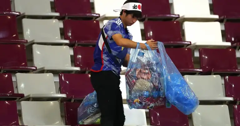 Persona recolectando basura en asientos de estadio de color borgoña