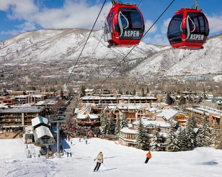 Esquiadores en Aspen con teleféricos rojos y vistas del pueblo y montañas