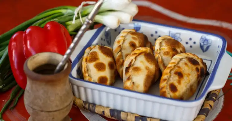 Empanadas argentinas caseras servidas con mate, cebolla de verdeo y pimiento rojo