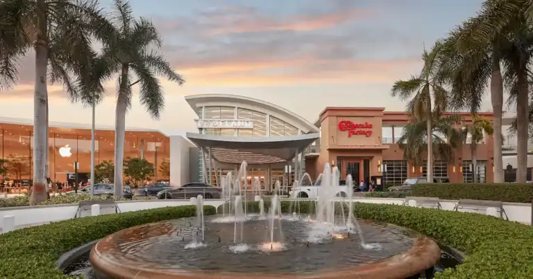 Entrada principal del Dadeland Mall en Miami con tiendas de lujo, fuente y palmeras.