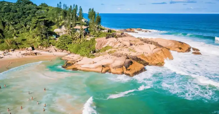 Playa con rocas doradas, agua turquesa y palmeras en colinas