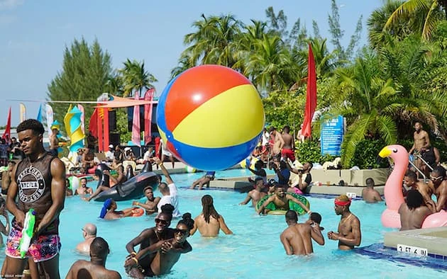 Piscina con personas disfrutando, flotadores coloridos y decoraciones con arco iris