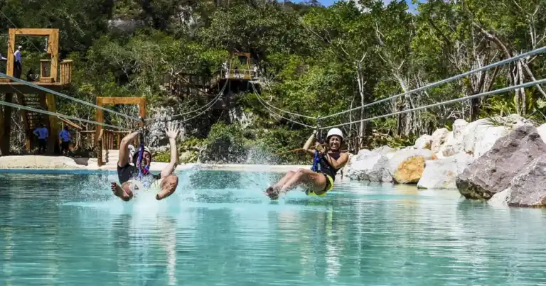 Personas saltando desde plataformas al agua turquesa en parque