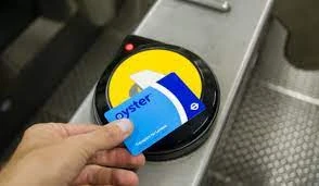 Mano sosteniendo tarjeta Oyster cerca de lector de pago en transporte público