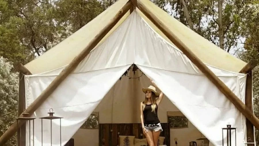 Carpa de glamping blanca de lona con mujer en la entrada