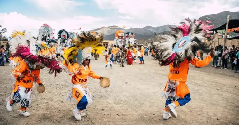 Niños bailando con tocados de plumas en una celebración folclórica andina al aire libre