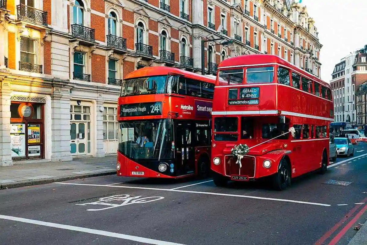 Dos autobuses rojos de dos pisos en calle de Londres con edificios históricos