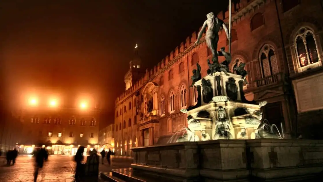 Plaza medieval iluminada con edificios históricos y pórtico con arcos