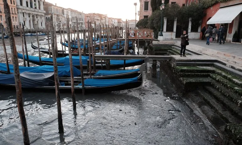 Góndolas azules amarradas en canal de Venecia con edificios históricos