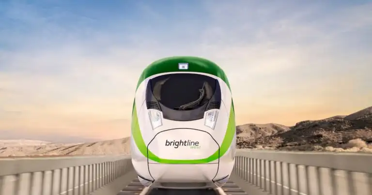 Tren Brightline verde y blanco en paisaje desértico montañoso