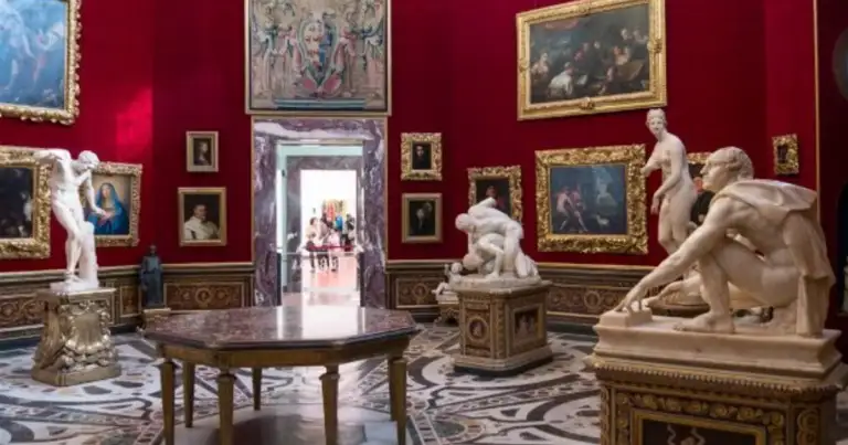 Sala de museo renacentista con paredes rojas, cuadros enmarcados y esculturas