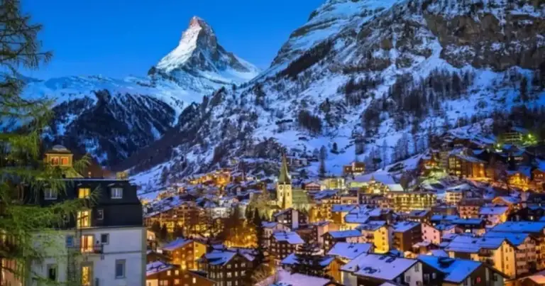 Pueblo alpino nevado con iglesia y montaña nevada al fondo