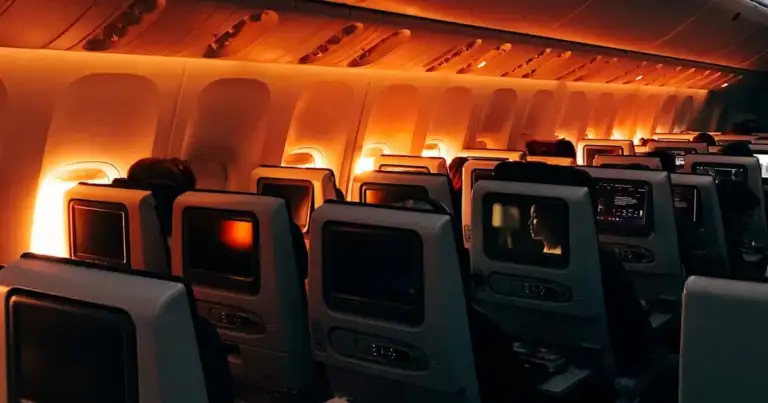 Filas de asientos de avión con iluminación naranja en la cabina