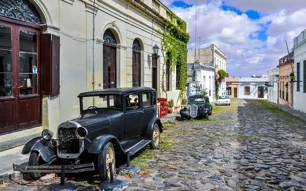 Calle de piedra colonial con auto vintage y edificios históricos