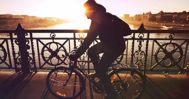 Ciclista en puente al atardecer con sol reflejado
