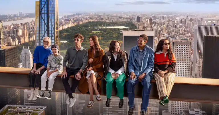 Seis personas sentadas en repisa elevada frente a vista panorámica de ciudad