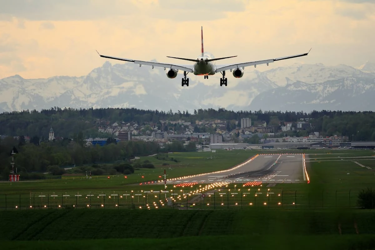 Avión aproximándose para aterrizar sobre pista rodeada de vegetación