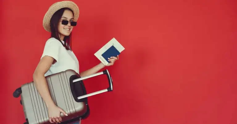 Viajera con sombrero de paja y gafas de sol, sujetando maleta rígida