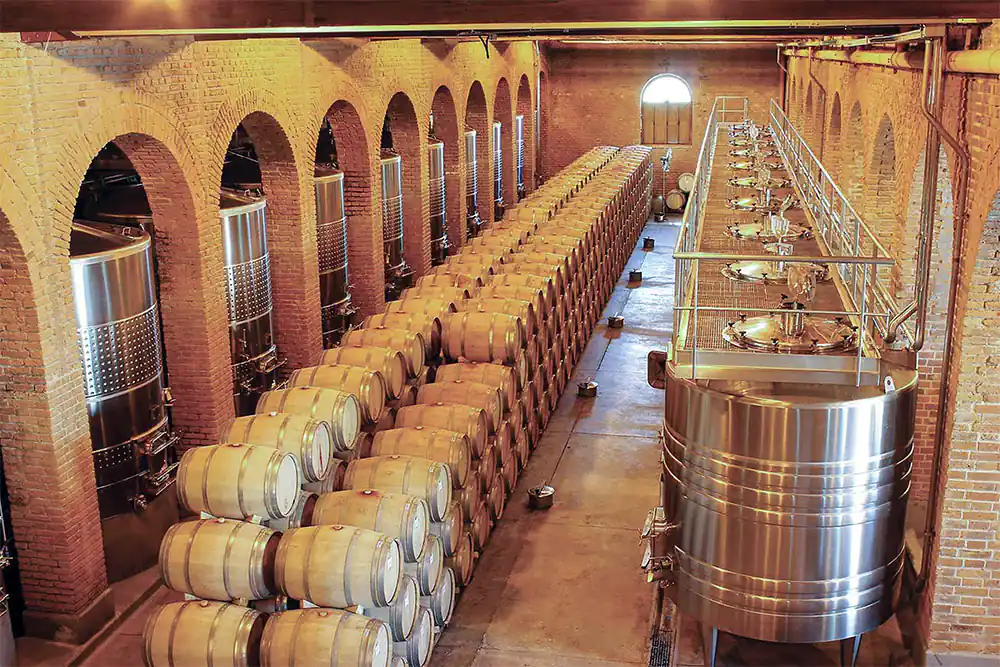 Interior de bodega con barriles de vino alineados en estantes de madera