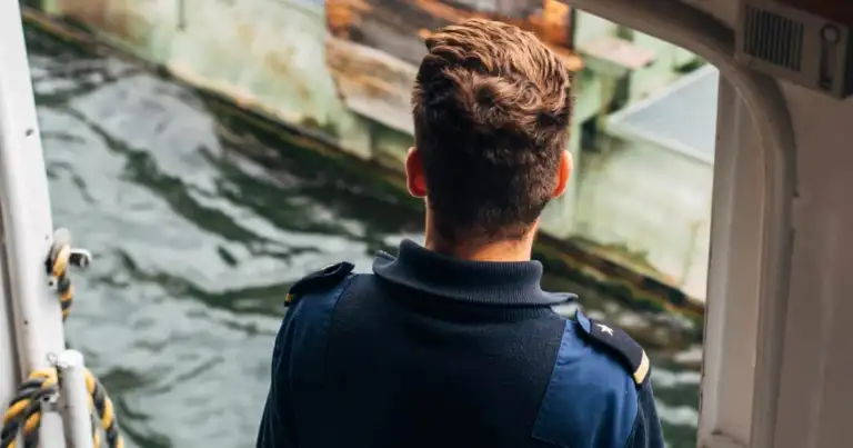 Hombre desde atrás observando el agua desde el riel de un crucero