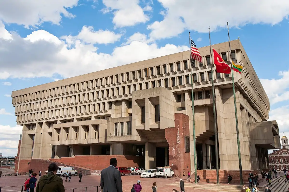 Edificio público contemporáneo de fachada pétrea con banderas en plaza