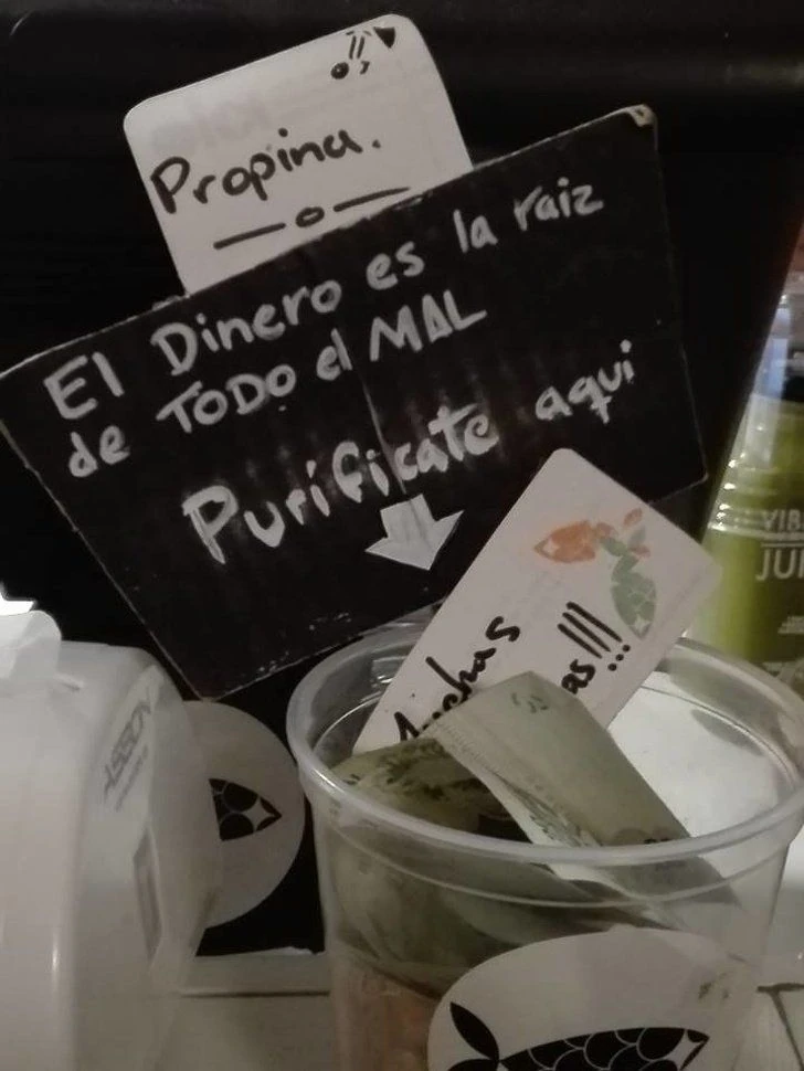 Recipiente para propinas con cartel humorístico sobre el dinero y las tips