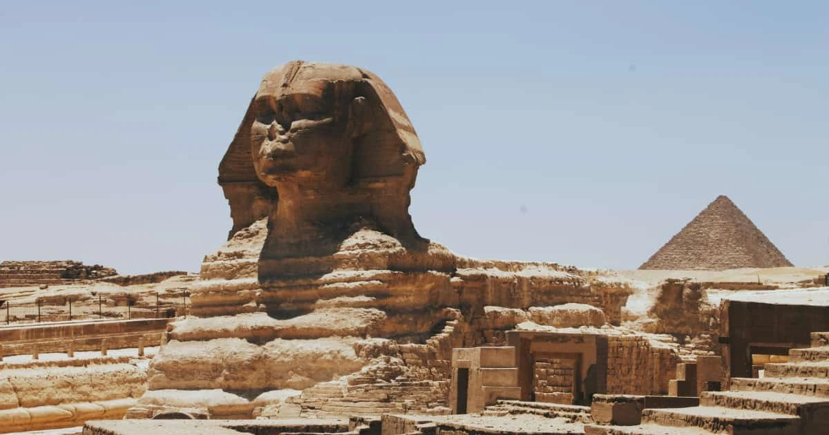 Gran Esfinge de Guiza de perfil con pirámides de Guiza al fondo