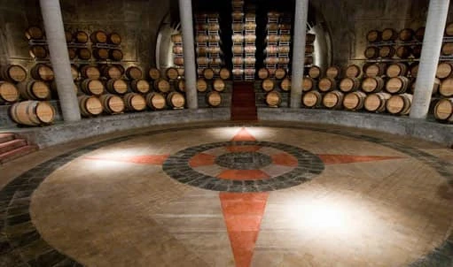 Cámara de barriles con suelo circular decorado y barriles de vino apilados