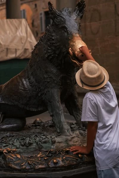 el niño tiene sombrero niño toca el hocico del porcellino para tener buena suerte