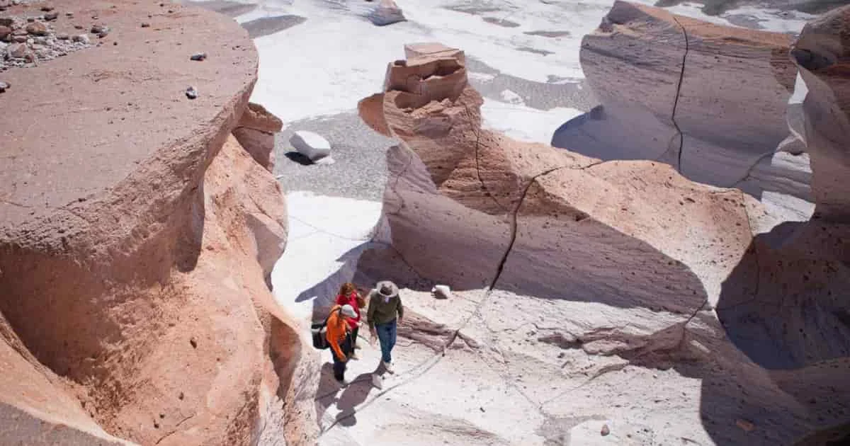 Dos excursionistas caminando entre formaciones rocosas desérticas