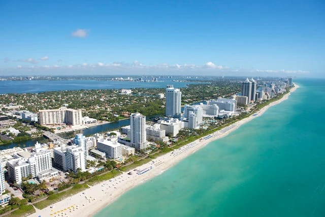 Vista aérea de Miami Beach con rascacielos frente al mar y playas de arena blanca.