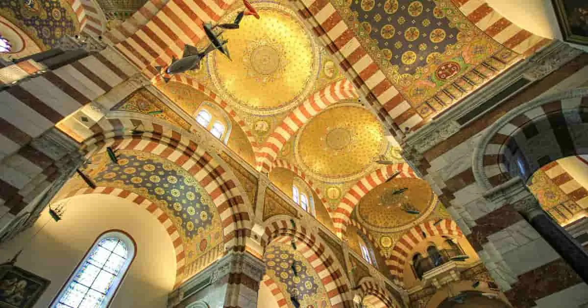 Interior de basílica con bóvedas decoradas y cúpulas doradas
