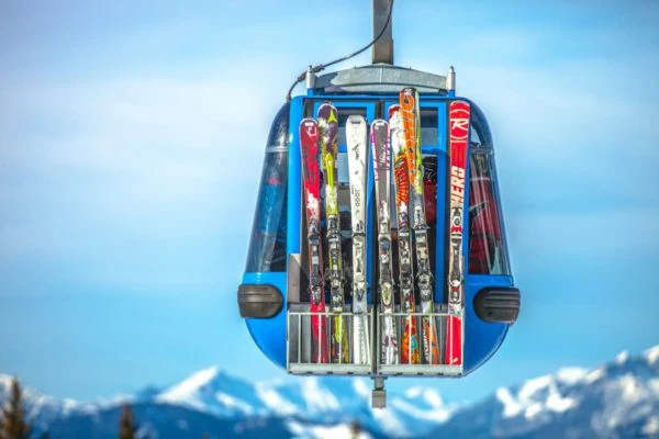 Esquís de colores en telesilla con montañas nevadas
