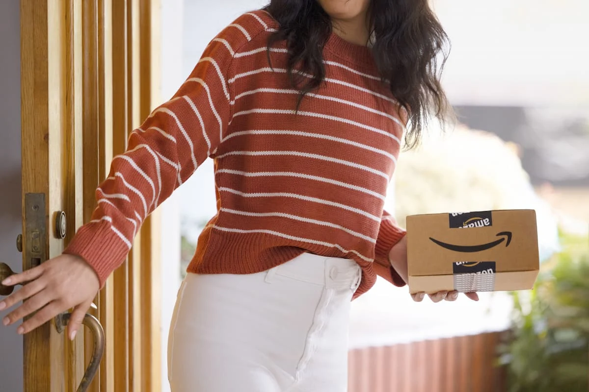 Persona con suéter rayas sosteniendo paquete de Amazon