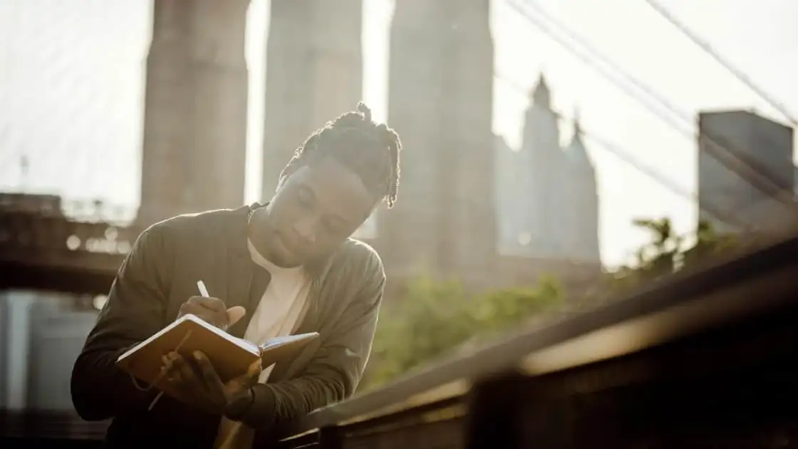 Persona leyendo libro con rascacielos al fondo bajo luz solar