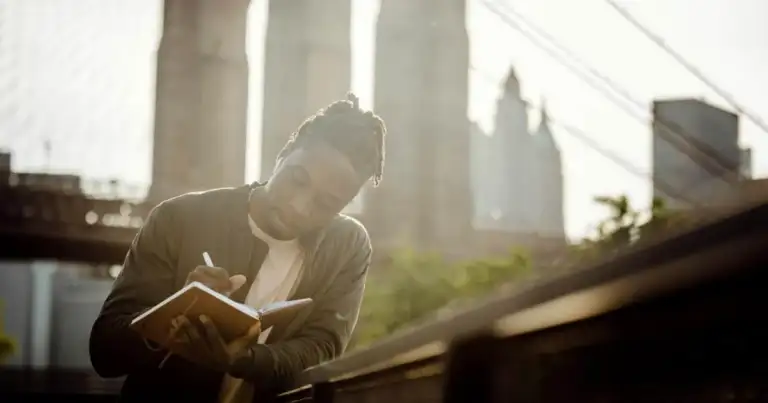 Persona leyendo libro con rascacielos al fondo bajo luz solar