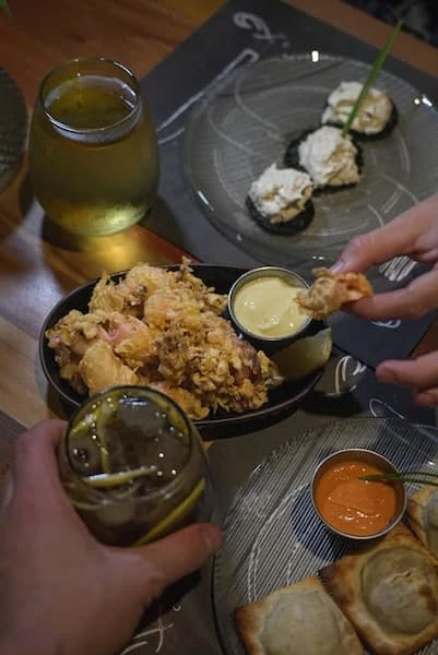 Mesa de tapas compartidas con croquetas, pan tostado y copas de vino blanco