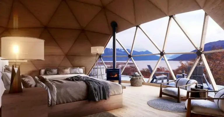 Interior de glamoroso alojamiento con cama, lámparas y vista a agua azul