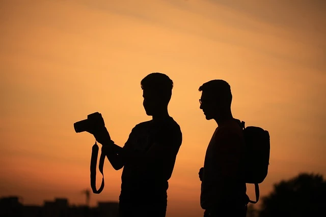 Aprovechar la escala para capturar el momento con fotografías al atardecer. creditos pixabay Dos viajeros observando una cámara al atardecer durante una escala de vuelo