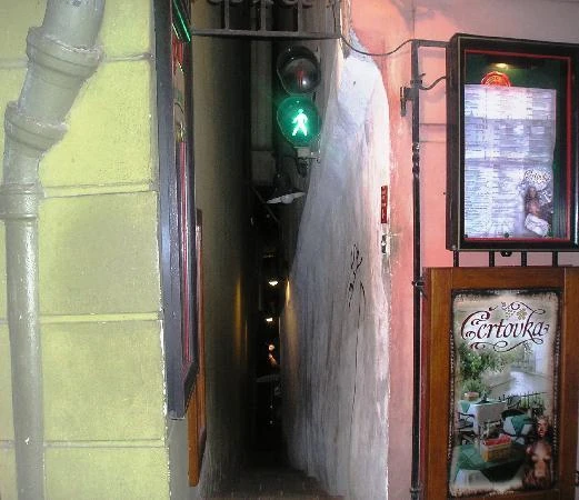 Calleja angosta entre edificios con semáforo verde encendido