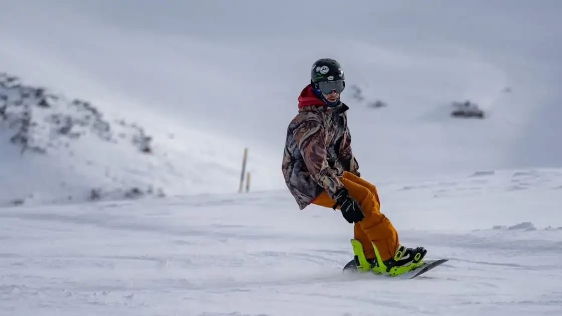 Persona en equipo de nieve practicando snowboard en ladera nevada