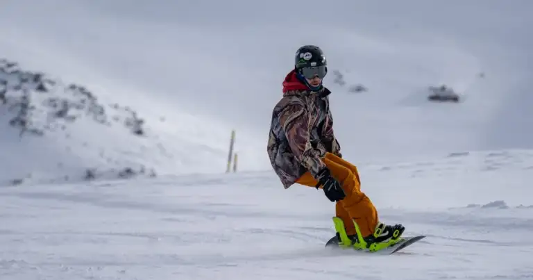 Persona en equipo de nieve practicando snowboard en ladera nevada