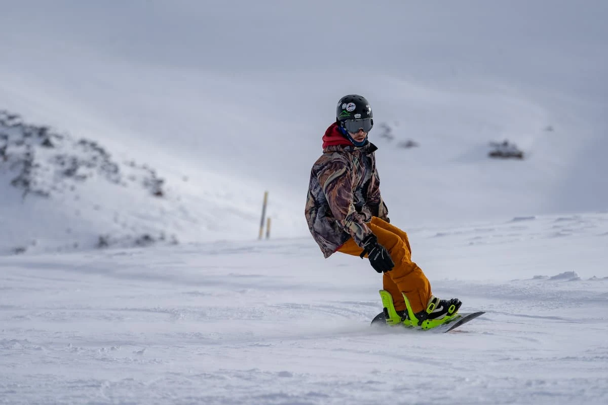 Persona en equipo de nieve practicando snowboard en ladera nevada